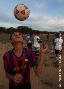 A boy tosses a football while other boys play behind him, in Oranjestad, the capital. A local retiree coaches the boys, who are from low-income families. One of the boys wears a shirt from the FC Barcelona football team that bears the UNICEF logo.  In September 2011, Aruba continues working to protect the welfare of its children since gaining autonomy from the Netherlands in 1986. Nevertheless, Aruba, like its sister islands in the Caribbean  Curacao and the Dutch portion of Sint Maarten  remains part of the Kingdom of the Netherlands, bound by its international treaties, including the Convention on the Rights of the Child (CRC). To assess the status of Arubas children, UNICEF was invited to undertake a situation analysis  UNICEFs core methodology to define child welfare in a given country, reviewing childrens situation in the context of an array of social, economic, political, institutional and historic factors. The aim was to evaluate progress and challenges in realizing childrens and womens rights in Aruba and to make recommendations for policies and social actions to improve these conditions. The analysis noted Arubas generally favourable economic status but also its high dependency on tourism, which provides limited employment options for islanders and makes them highly vulnerable to steep downturns in the global economy. It also showed the benefits of the islands universal health care: over 99 per cent of women receive antenatal care; more than 95 per cent of births are overseen by skilled attendants; vaccination coverage among children between 12 and 23 months old has reached 90 per cent, and all children have access to safe drinking water and improved sanitation facilities. Nevertheless, obesity affects 35 per cent of children, heralding future health problems, and rising rates of adolescent pregnancy are causing increased health and social complications. In education, nearly all children aged 611 years attend primary school. However, the absence of laws requiring post-secondary attendance contributes to high dropout rates for adolescents, which, in turn, contributes to the numbers of youth involved in gangs or substance abuse. Current policy also mandates Dutch  in which only 5.8 per cent of the population is fluent  as the principal language of instruction, instead of Papiamento, a Creole language spoken by 66.3 per cent of inhabitants. Language barriers are compounded for the 30 per cent of the population who are new immigrants, most of whom speak neither Dutch nor Papiamento. A preponderance of low-wage jobs and inadequate childcare also contribute to rising reports of child abuse. UNICEF recommendations note the need for a more diversified economy that promotes social welfare as well as growth and for continued reporting and visibility for childrens issues to support positive change. It also recommends improved interaction and coordination between state, social, private and union sectors to implement policies addressing the language of educational instruction, high school attendance, childhood obesity, protections against abuse and domestic violence, as well as the needs of diverse cultures.