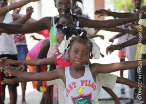 On 23 April, children exercise during a recreation activity at the Parc Jean Marie Vincent sports centre in the Piste Aviation neighbourhood of Port-au-Prince, the capital. The area is serving as a temporary settlement site for an estimated 25,000 people displaced by the earthquake. The recreation programme provides structured daily sports activities, as well as psychosocial support, for young people. It is managed by the Haitian Olympic Committee, with support from the Government, UNICEF and other partners. Most open spaces in the city are now occupied by the displaced.  By early May 2010 in Haiti, emergency responses had shifted to long-term recovery efforts in response to the 7.3 magnitude earthquake that hit the country on 12 January. The quakes epicentre was only 17 kilometres from Port-au-Prince, the capital, more than 222,500 people were killed and 1.3 million, of whom 450,000 were children, became homeless. In Port-au-Prince, more than 619,000 people continue to live in makeshift settlements, despite an exodus of over 604,000 from the devastated city. The towns of Léogâne and Jacmel were also heavily damaged; and social infrastructures in rural communities, which now host some of the displaced, are over-strained. In the capital, major government and private infrastructure have been destroyed or heavily damaged, including hospitals, water, sanitation and electrical systems, and telecommunications, banks and transportation networks. UNICEF is working with the Government, other UN agencies, international and local NGOs and private partners to help rebuild  with special focus on the estimated 46 per cent of Haitis nearly 10 million inhabitants who are under age 18. UNICEF is the lead coordinating agency for nutrition, WASH (water, sanitation and hygiene) and child protection; UNICEF also shares lead coordinating duties on education with Save the Children, and is a key health partner. This latest catastrophe has exacerbated Haitis already critical humanitarian situation. Prior to the quake, more than 78 per cent of the population lived on less than US $2.00 a day. UNICEFs portion of the Feuary 2010 United Nations Haiti Revised Humanitarian Appeal (totalling US $1.44 billion) is US $222.8 million, most of which has been received. But while international donors have pledged some US $5.3 billion to support all aspects of Haitis recovery over the next 18 months, an estimated US $11.5 billion is required to meet projected needs.