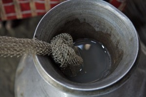 Rozina, 15, treats ackish water with aluminium sulphate ('alum') wrapped in fishing net at her home in the village of Padma in Borguna District. Rozina lives with her parents and two younger siblings. During Cyclone Sidr, their home and village were submerged and the pond they used for drinking water was polluted. They must now drink water from the Baulestar River, which feeds directly into the saltwater Bay of Bengal. To make it safer, Rozina first uses a piece of cloth as a filter against mud and rocks. She then treats the water with aluminium sulphate ('alum'), which causes dirt and other particles to settle so that clear water can be decanted. Today she will also add a UNICEF-provided water purification tablet to kill bacteria and prevent water-bourne diseases. 