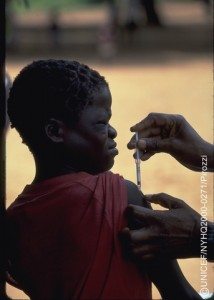 A boy grimaces as he receives a needle vaccination from a health worker during a two-day immunization session for all 5,000 people at the Wenela camp who have been displaced by the flooding, in the district of Chibuto, in the province of Gaza. Both children and adults are being vaccinated, as needed, against measles, tetanus and meningitis, and children are being given vitamin A capsules to boost their natural immune systems.  By mid-March 2000 in Mozambique, relief and rehabilitation efforts were well under way in response to the worst flooding in 50 years that followed torrential rains in late Feuary, affecting at least seven provinces, causing some 500 deaths and leaving more than 300,000 people homeless or without a livelihood. UNICEF is working with the Government, NGOs, other UN agencies and foreign governments to respond to the emergency and has also supported a Ministry of Health mass vaccination campaign targeting tens of thousands of children and adults in three provinces in the Limpopo River valley, one of the most severely affected areas. Providing vaccinations against measles, meningitis and tetanus, as well as vitamin A capsules (to reinforce immune systems) for an estimated 45,000 children, the two-week campaign demonstrated the logistical challenges faced to vaccinate people in remote areas.