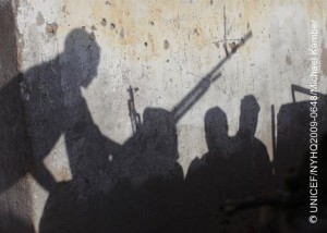 Militia members, holding guns and standing on a truck with a heavy machine gun, cast shadows against a wall in central Somalia. They have been hired by the local government to provide security in the community. Though the immediate area is currently peaceful, nearby hostilities are present a constant threat to stability.  By April 2009 in Somalia, drought and armed conflicts had displaced some 1.2 million people, contributing to a nutrition crisis that leaves one in six children under the age of five acutely malnourished. The country remains one of the three poorest in the world, and is the second-worst affected by recent volatility in food prices. Forty-three per cent of the population  including 1.4 million children  requires humanitarian assistance, but chronic conflict among armed groups limits humanitarian access to vulnerable populations. UNICEF and partners currently provide water to 250,000 displaced people and nutritional support to over 100,000 children per month. Nevertheless, over 300,000 children are expected to experience acute malnutrition over the course of the year. The region worst affected by the drought and conflict is the Central and Southern Zone, where humanitarian aid workers are also being targeted.