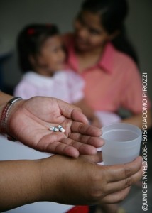 A health worker holds ARV medications and a glass of water in her hands at a child care centre in Tondo, a neighbourhood of Manila, the capital. Behind her, an HIV-positive child sits with a caregiver. The centre is run by Precious Jewels Ministry, a UNICEF-assisted centre NGO that offers medical assistance, educational activities and counselling for AIDS-affected children, as well as community outreach to raise awareness of HIV/AIDS and combat the stigma associated with the disease.  In 2006 in the Philippines, HIV transmission is hidden and growing. While official statistics cite fewer than 10,000 HIV cases nationwide, high-risk behaviours, especially among adolescents, are on the rise. Those at highest risk are children in depressed, urban areas, those who live or work in the streets and those involved in the sex industry. Many have limited access to basic services like education, community support and health care. And a strong culture of stigma, denial and silence has prevented an open discussion of HIV/AIDS, sexuality and adolescent reproductive health. Other factors impeding prevention and care services include limited knowledge and skills among health-care workers; rapid turnover and migration of staff; and disruption of health systems due to emergencies and conflict. On Mindanao Island, a decades-long conflict between Christians and Muslims has killed, injured or displaced thousands of children, and left others vulnerable to abduction, trafficking and abuse. Working with government, NGO and other partners, UNICEF supports peer counselling and prevention awareness training for adolescents; expanded voluntary counselling and testing services; and treatment, care and support services for children infected with HIV/AIDS. UNICEF also supports child protection, peace building and the delivery of social services in conflict areas.