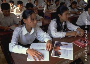 Literature showing the impact of AIDS lying on their desks, adolescent girls and boys listen to a presentation on AIDS awareness and prevention, part of a student-to-student education exchange initiative supported by UNICEF, in a village in the south-eastern province of Svay Rieng. In 2000 in Cambodia, after more than a decade of intermittent peace, the country is continuing its recovery from 30 years of conflict, including genocide. Despite progress in health and nutrition, maternal and infant mortality rates are the highest in south-east Asia, most of the predominantly rural population still lacks access to essential services, and problems of ongoing violence, displacement and landmines continue to take their toll. HIV/AIDS is spreading rapidly, accelerated by a growing commercial sex industry, with an estimated 35 per cent of sex workers under 18 years of age, almost half of whom are presumed to be HIV positive. With half of the country's population under 18 years of age, these indicators represent a major threat to their future, including increased rates of mother-to-child transmission. UNICEF programmes to help combat the spread of HIV/AIDS include support for prevention and awareness programmes to all social sectors, including student-to-student education exchanges, the provision of testing and counselling services, and improved access to recovery and care for affected children and families.