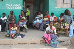 [RELEASE OBTAINED] Patients wait outside the Samfya Stage 2 Clinic, in the rural town of Samfya, in Samfya District. The clinic provides PMTCT services as well as other child and maternal health services.  In October 2010 in Zambia, clinics in both urban and rural areas are providing vital programmes to treat HIV-positive pregnant women and to prevent mother-to-child transmission of HIV (PMTCT). PMTCT programmes include HIV testing during pregnancy, antiretroviral (ARV) regimens for sick HIV-positive pregnant women, and early diagnosis and treatment for infants exposed to HIV in utero. These infants receive prophylactic antibiotics and ARVs in the weeks after they are born and are administered HIV tests at six weeks. If eastfed by an HIV-positive mother, infants continue to receive prophylactics and are tested again at 12 months and 18 months (and three months after eastfeeding ceases or at any age if they fall ill). HIV-positive infants diagnosed and treated within the first 12 weeks of life are 75 per cent less likely to die from the disease. However, many infants do not receive PMTCT services because their caregivers lack access to properly equipped facilities or fear the stigma associated with HIV. Zambia has recently made great strides in expanding PMTCT programmes. In the second quarter of 2009, ARVs were administered to approximately half of all children in need and to some 57 per cent of HIV-positive pregnant women. But for PMTCT measures to be effective, infants must adhere to a long-term, structured course of tests and services. Access to PMTCT services is particularly difficult in rural areas, where poverty rates are higher and many remote communities have limited access to health clinics. UNICEF supports the expansion of these services into rural areas, including Samfya District in Luapula Province. The province has the highest child-mortality rates in the country, and Samfyas clinics face critical staff and supply shortages. However, rural areas also tend to have lower HIV infection rates, as well as greater willingness on the part of fathers to participate in PMTCT services.