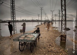 On 13 September, a boy pushes a cart along a narrow strip of land between utility poles and expanses of flood water, in the city of Hyderabad, Sindh Province.  By 26 September 2011 in Pakistan, over 5.4 million people  including 2.7 million children  had been affected by monsoon rains and flooding, and this number was expected to rise. In Sindh Province, 824,000 people have been displaced and at least 248 killed. Many government schools have been turned into temporary shelters, and countless water sources have been contaminated. More than 1.8 million people are living in makeshift camps without proper sanitation or access to safe drinking water. Over 70 per cent of standing crops and nearly 14,000 livestock have been destroyed in affected areas, where 80 per cent of the population relies on agriculture for food and income. Affected communities are also threatened by measles, acute watery diarrhoea, hepatitis and other communicable diseases. The crisis comes one year after the countrys 2010 monsoon-related flooding disaster, which covered up to one fifth of the country in flood water and affected more than 18 million people, half of them children. Many families are still recovering from the earlier emergency, which aggravated levels of chronic malnutrition and adversely affected primary school attendance, sanitation access and other child protection issues. In response to this latest crisis, UNICEF is working with Government authorities and United Nations agencies and partners to provide relief. Thus far, UNICEF-supported programmes have immunized over 153,000 children and 14,000 women; provided nutritional screenings and treatments benefiting over 2,000 children; provided daily safe drinking water to 106,700 people; and constructed 400 latrines benefiting 35,000 people. Still, additional nutrition support and safe water and sanitation services are urgently needed. A joint United Nations Rapid Response Plan seeks US$356.7 million to address the needs of affected populations over the next six months. Only US$9 million has been received so far.