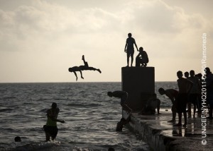 On 10 June, boys dive into the coastal waters of the Mediterranean Sea, in the city of Benghazi. By 15 June 2011, over one million people had fled the conflict between government and rebel forces in the Libyan Arab Jamahiriya, and an estimated 243,000 had been displaced within the countrys borders. Intense fighting continues, particularly near the cities of Brega and Misrata and in the Nafusa Mountains. United Nations inter-agency missions to Tripoli, the capital, and to Misrata have confirmed that children are experiencing increased stress and anxiety. Conflict zones are also experiencing medicine shortages; UNICEF has delivered vaccines and other medical supplies to some areas in need. In the eastern city of Benghazi, which is controlled by rebel forces, children and their families exist in an interregnum between peace and war. Many have sought refuge from other parts of the country, and many men of these families are away fighting. UNICEF and partners are assisting the provision of safe water in the city and supporting workshops to raise awareness of the risks to children and others of explosive remnants of war (ERW). Child protection workshops are training volunteers to provide psychosocial support to children. Workshops will be expanded to other parts of the country as access to other areas is restored. Most formal education has been halted since the onset of the crisis. In Benghazi, UNICEF is working to provide recreational and educational activities for children. The mass exodus from Libya including over 550,318 people who have escaped to Tunisia and over 347,900 who have fled to Egypt has also created emergency conditions in neighbouring countries. To address the regional crisis, a joint United Nations flash appeal for US$407 million has been issued; UNICEFs portion of the appeal is US$20 million.