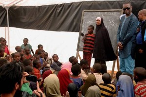 On 5 September, UNICEF Goodwill Ambassador Youssou NDour (second from right) listens to children sing at Illeys Primary School, in the Dagahaley refugee camp in the north-eastern town of Dadaab. The school is operated by the NGO Care International.  From 5 to 7 September 2011, UNICEF Goodwill Ambassador Youssou NDour visited Kenya to focus renewed attention on the regions drought crisis, which continues to threaten the lives of 12.4 million people across the Horn of Africa. In Kenya, the number of people who are food insecure has increased from 2.4 million to 3.75 million, and food prices are at a record high. Some 385,000 children and 90,000 pregnant and lactating women now suffer from acute malnutrition in the countrys arid and semi-arid areas, and nationwide, the percentage of children at risk of acute malnutrition is growing. Cholera, dysentery, malaria and measles have been reported in the country, and rural communities are experiencing widespread livestock losses and conflict over pasturelands and water. A concurrent humanitarian crisis is unfolding in northern Kenya, where over 400,000 Somali refugees  56 per cent of them children  have sought shelter in the Dadaab refugee camps. Mr. NDour, a world-renowned singer and long-time child advocate, visited refugees at the Dadaab camps, where UNICEF supports immunization efforts, therapeutic feeding and temporary learning spaces for children. He also visited the camps host community in the drought-affected town of Labisigale, where UNICEF provides water and sanitation services. UNICEF, together with the Government, UN, NGO and community partners, is supporting a range of interventions throughout the region. A joint United Nations appeal for humanitarian assistance for the region requires US $2.4 billion, of which 59 per cent has been funded to date. A majority of UNICEFs portion of the appeal has been funded.