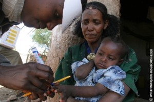 As her mother watches, a man health worker marks a girl's fingernail to indicate that she has received a dose of oral polio vaccine, during the door-to-door polio NIDs in the village of Beles in Tigray Region. [#5 IN SEQUENCE OF SIXTEEN]  From 1 to 5 April 2005 in Ethiopia, the first of two rounds of National Immunization Days (NIDs) against polio this year targeted 14.7 million children under five. Although Ethiopia had been polio-free for four years, the current NIDs are in response to two cases of polio detected in children in the Tigray Region in December 2004 and early January 2005. Some 100,000 volunteers and health workers are participating in the campaign which will go door-to-door in an effort to reach all children. UNICEF is providing 21 million doses of vaccine for the campaign. The Ethiopian outeak is part of a larger outeak in many previously polio-free African countries, following the suspension of polio immunization campaigns for several months in northern Nigeria in late 2003 and part of 2004 that caused a surge of new cases. Mass vaccinations resumed in Nigeria early this year and NIDs against the disease are now underway in 22 African countries, aimed at reaching 100 million children.