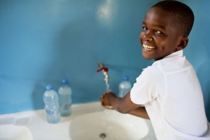 Hans Hasan, a participant of the SWASH club; poses for a photograph while washing her hands at Kingugi School in Dar es Salaam, Tanzania Wednesday, April 2, 2014. The WASH club teaches childrenthe importance of hand washing before eating and after visiting the toilet and encourages children to educate their families and peers of the imporance of having clean hands.