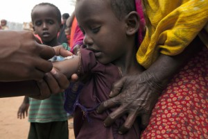 On 2 August, a community health worker vaccinates a child during the UNICEF-supported measles and polio immunization campaign under way in the Ifo refugee camp in North Eastern Province, near the Kenya-Somalia border. The camp for Somalia refugees is among three that comprise the Dadaab camps, located near the town of Dadaab in Garissa District. By 2 August 2011, the crisis in the Horn of Africa  affecting primarily Kenya, Somalia, Ethiopia and Djibouti  continues, with a worsening drought, rising food prices and an ongoing conflict in Somalia. More than 12 million people are threatened by the regions worst drought in 60 years. Somalia faces one of the worlds most severe food security crises as it continues to endure an extended humanitarian emergency, with tens of thousands fleeing into Kenya and Ethiopia. More than 10,000 Somalis a week are now arriving in the Dadaab camps in north-eastern Kenya, where aid partners are struggling to meet the needs of 400,000 people. In drought-affected areas of Kenya, Somalia, Ethiopia and Djibouti, some 500,000 severely malnourished children are at imminent risk of dying, while a further 1.6 million moderately malnourished children and the wider-affected population are at high risk of disease. In northern Kenya, more than 25 per cent of children suffer from global acute malnutrition. UNICEF, together with Governments, UN, NGO and community partners, is supporting a range of interventions and essential services, especially for the displaced and for refugees, including feeding programmes, immunization  mass vaccination campaigns are now underway in drought-affected parts of Kenya and Somalia  and other health outreach, as well as access to safe water and to improve sanitation. In Kenya, the Ministry of Health, UNICEF and the World Health Organization (WHO) have reached 290,000 children with polio and measles vaccinations in refugee host communities near the Dadaab camps. UNICEF is providing the vaccines, as wel