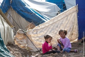 Iraq, May 2013. Two Syrian girls plays behind the tent in the Domiz refugee camp in Northern Iraq. The area is strewn with rubbish and often raw sewage but children have nowhere else to go to play. Domiz is situated near the city of Dohuk, about forty miles from the Syrian border. Approximately 40,000 Syrians are living here, in facilities provided for around half that number. April 2013 marked one year since Domiz camp opened in Dohuk, Northern Iraq. In that time it has grown to a tent city of nearly 40,000 Syrian refugees. UNICEF provides services in education, child protection, water, sanitation and hygiene, and health and nutrition. UK Nat Com local copies of these files at \Unicef-mediaphotosCOUNTRIESsyriaSY2013-refugees-IRAQ