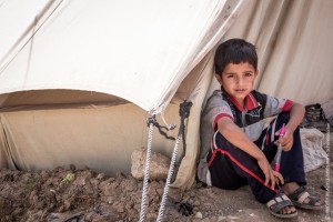 Iraq, May 2013. A young Syrian boy sits in front of his family's tent in the Domiz refugee camp in Northern Iraq. Domiz is situated near the city of Dohuk, about forty miles from the Syrian border. Approximately 40,000 Syrians are living here, in facilities provided for around half that number April 2013 marked one year since Domiz camp opened in Dohuk, Northern Iraq. In that time it has grown to a tent city of nearly 40,000 Syrian refugees. UNICEF provides services in education, child protection, water, sanitation and hygiene, and health and nutrition. UK Nat Com local copies of these files at \Unicef-mediaphotosCOUNTRIESsyriaSY2013-refugees-IRAQ