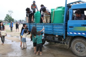 On 28 April, children, some filling water bottles, get drinking water from workers in a truck, during a distribution in a camp for people displaced by the massive earthquake, in Kathmandu, the capital. On 28 April 2015 in Nepal, search, rescue and relief operations continue in the aftermath of the massive 7.8 magnitude earthquake that hit the country on 25 April. The quakes epicentre was 80 kilometres from Kathmandu, the capital. At least 3,351 people have been killed, 6,833 have been injured, and 8 million people in 39 districts have been affected. The Government has declared a state of emergency in 35 affected districts in the country, where more than 1.3 million people  over half of whom are children  are affected by the disaster. Homes and vital infrastructure, including hospitals, have been severely damaged or destroyed, leaving thousands of children and families homeless, vulnerable and in urgent need of food, shelter, safe water and sanitation, and health support. Over 1.4 million people are in need of food assistance. Most of the displaced are sheltering in camps or in available open spaces. The situation has been exacerbated by continuing powerful aftershocks that have caused additional damage. Working with the Government and other partners, including fellow United Nations organizations, UNICEF is supporting water, sanitation and hygiene (WASH), health, nutrition, child protection, education and other interventions. In response to the disaster, UNICEF is providing hospitals tents, tarpaulin sheeting, emergency medical kits, vaccines and related supplies, zinc and oral rehydration salts to prevent diarrhoeal disease outeaks, and temporary learning spaces and psychosocial counselling for children. UNICEF is also procuring emergency health kits and is supporting water trucking services in camps for the displaced.