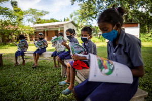 Children study while they follow social distancing in the open area at a primary government school in India